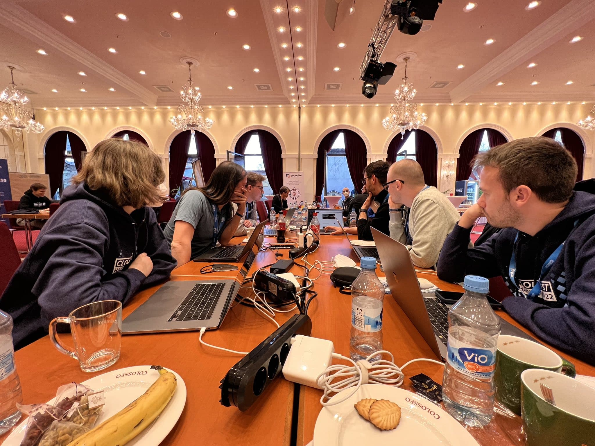 a collection of people sitting at a table with laptops in front of them